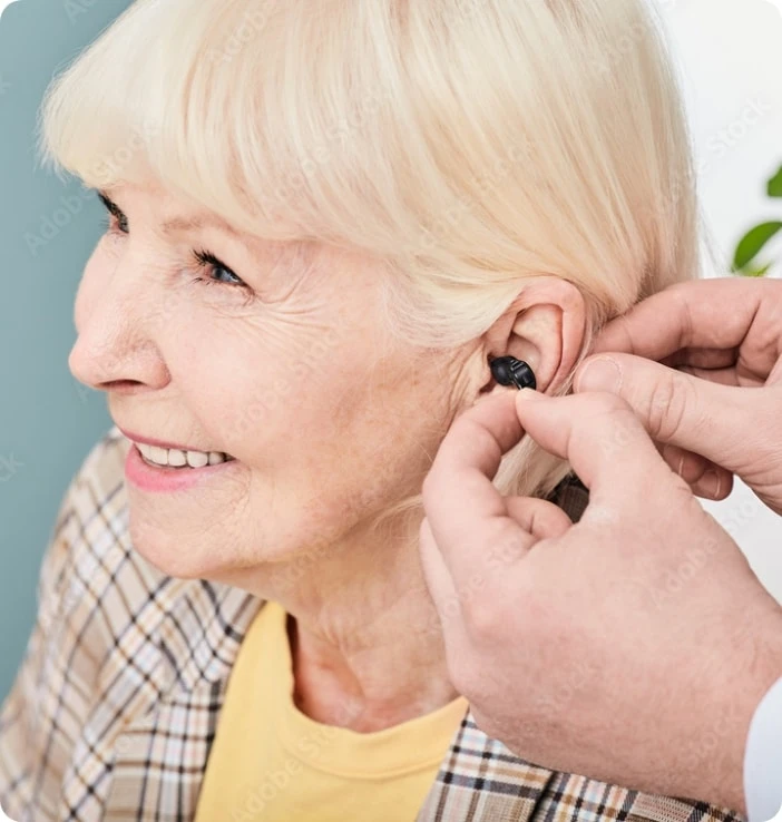 Audioprothésiste insérant un appareil intra-auriculaire à une patiente senior