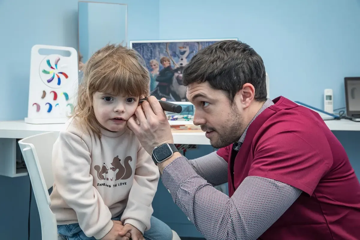 Audioprothésiste adaptant un appareil auditif sur une petite fille